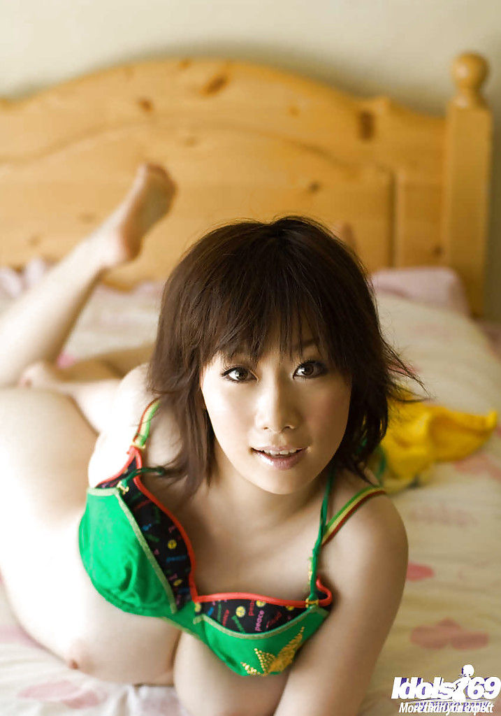 Японская девушка обнажает и гладит свое тело на кровати